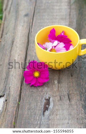 cut lilac flowers in the yellow mug on the wood board