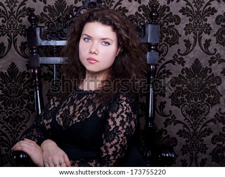 sad aristocratic woman in the black dress sit in the wood chair