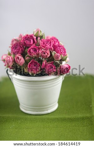 bouquet of pink roses in a decorative bucket on a green background