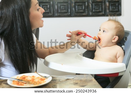 Mother feeding hungry six month old baby solid food