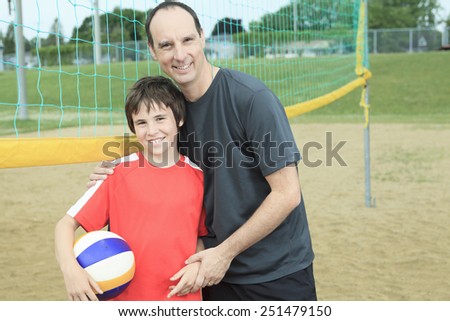 Portrait of happy family holding volleyball outside