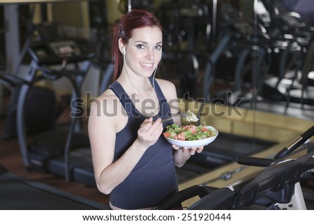 Gorgeous young woman at the gym eating salad
