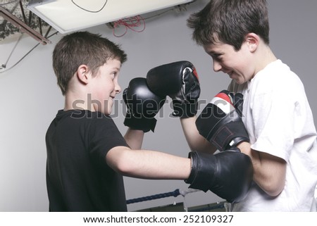 young boy with black boxing gloves fight with his brother