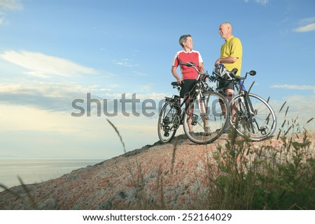A senior man and a woman on bike at the sunset.