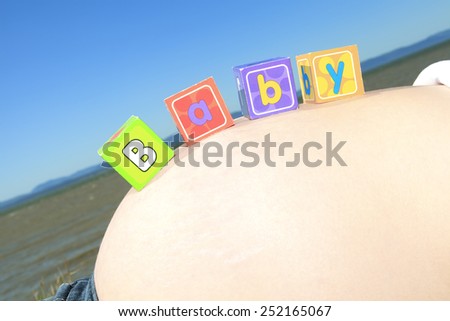 Alphabet blocks spelling BABY on a pregnant belly