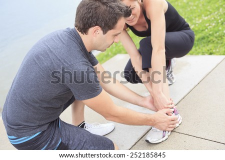 Injury - sports woman with twisted sprained getting help from man touching her ankle.