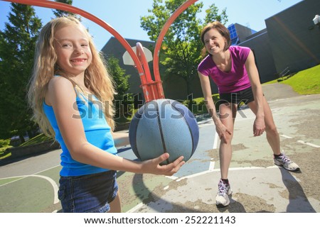 A mother play basketball with his daughter