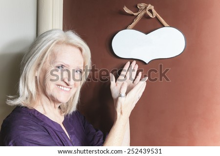 A senior woman pointing a heart on a door.