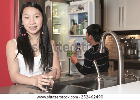 A teenager girl drinking water in the kitchen