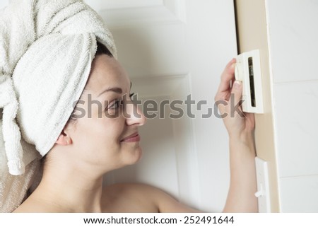 A woman in shower rise up thermostat.