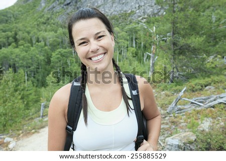 Female hiker with backpack walking and smiling on a country trail