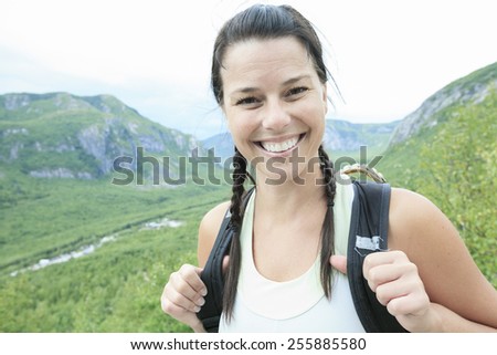 Female hiker with backpack walking and smiling on a country trail