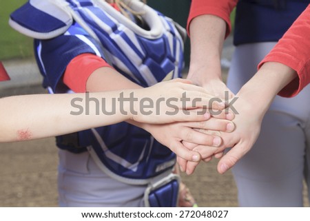A baseball team puting hand together