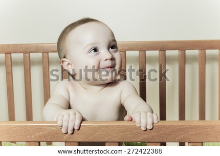 A Funny little baby with beautiful standing in a round white crib