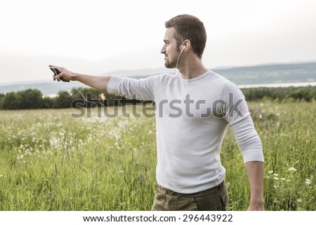 A Happy young man in a field with his cellphone