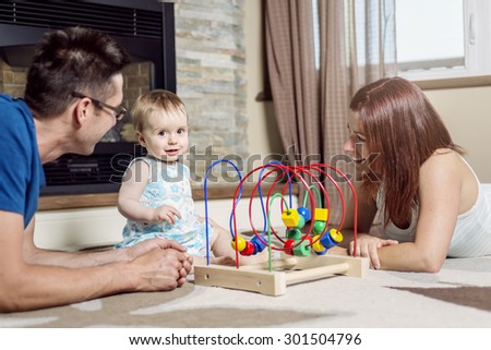 A parents baby sitting on floor play with toy