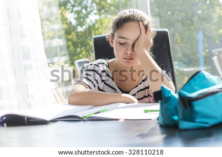 A schoolgirl studying with books on the kitchen table