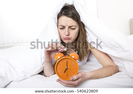 A Young sleeping woman and alarm clock in bedroom at home