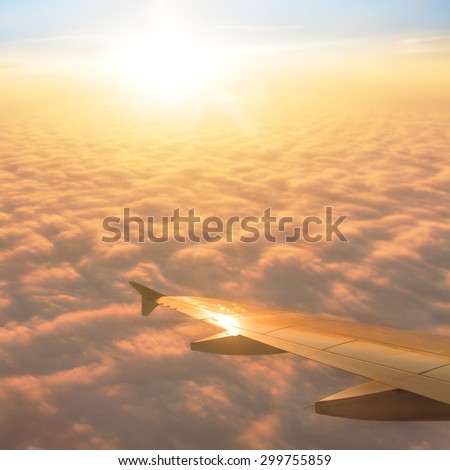 Plane window with blue sky and clouds outside
