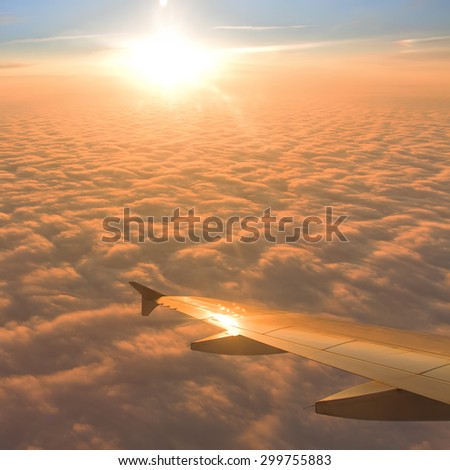 Plane window with blue sky and clouds outside