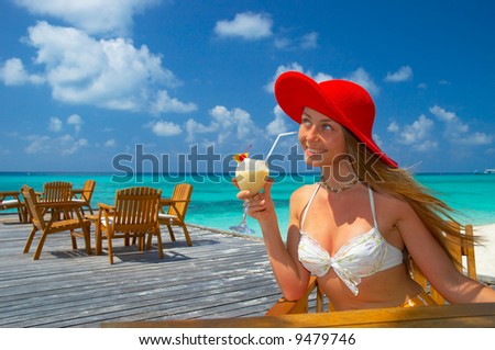 woman in red hat sitting in the chair drinking cocktail