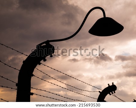 Lamp silhouette in concentration camp. It is part of barwire fence.