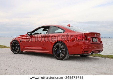 TAMPA, FLORIDA/USA - JANUARY 18 2015: The brand new 2015 BMW M4 parked near a beach in Tampa, FL. This Sakhir Orange M4 has a 6 cylinder twin turbo engine as well as the upgraded 19 inch black wheels.