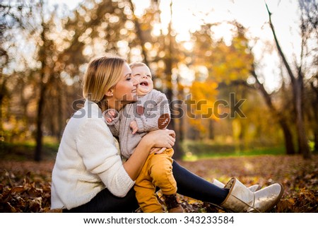 Happy woman and her little son having fun in an autumn park