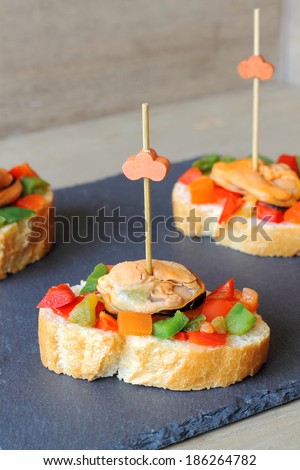 Pinchos or pintxos, traditional Spanish tapas made with small slices of bread topped with mussels vinaigrette and fastened with a skewer