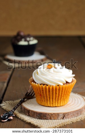 Delicious carrot cake and chocolate cupcakes on a wooden rustic table