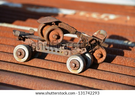 Vintage metal roller skates on a rusty tin roof