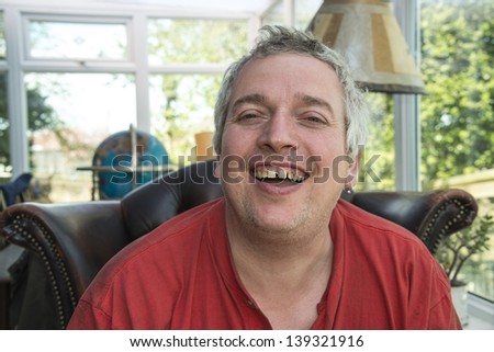 A grey haired man with large teeth laughing