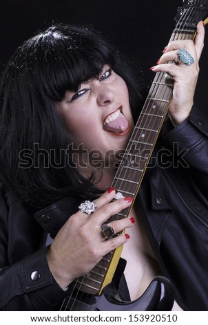 A rock chick with electric guitar tongue out with attitude