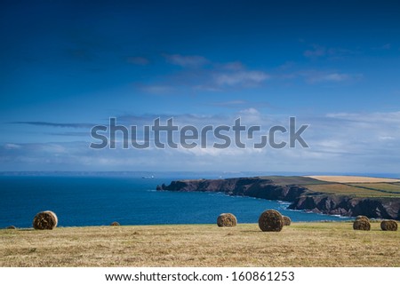 Hay bales in a welsh coastal field with the sea in the distance