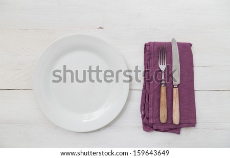 White plates and silverware on a light wood background