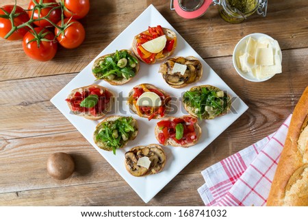 Bruschetta with beans and arugula, mushrooms, goat cheese on a wooden board