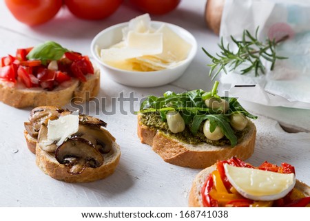 Bruschetta with beans and arugula, mushrooms, goat cheese on a wooden board