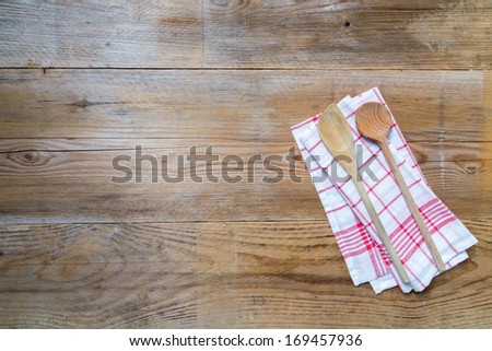 Red kitchen towel with cooking spoons on wooden wooden background