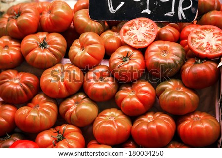 Many beefsteak tomatoes on a market stall.