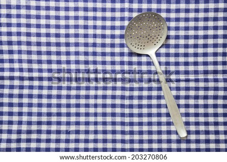 slotted spoon and dish cloth as background.
