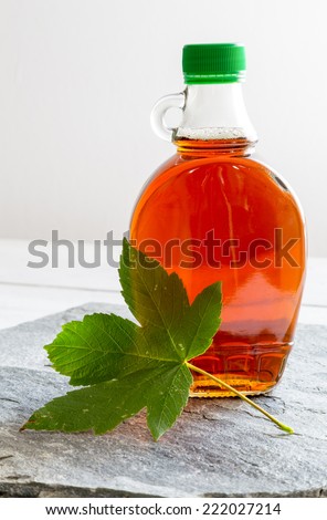 Maple syrup in a bottle on stone plate.