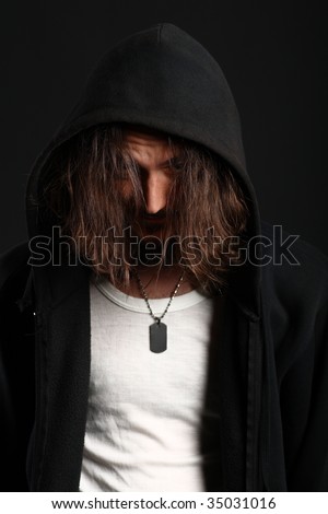 Portrait of young man in hood hiding behind long hair