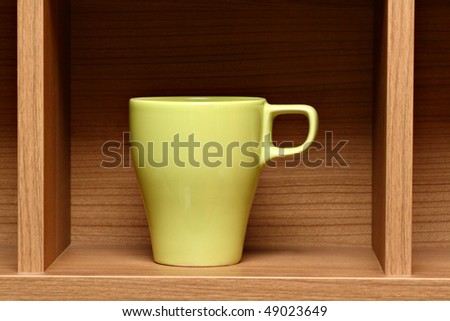 Light green coffee cup on wooden shelf