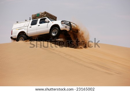 White off-road car fetching a dune, side view