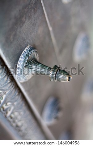 Closeup detail of a metal detail piece on a thick metal door.