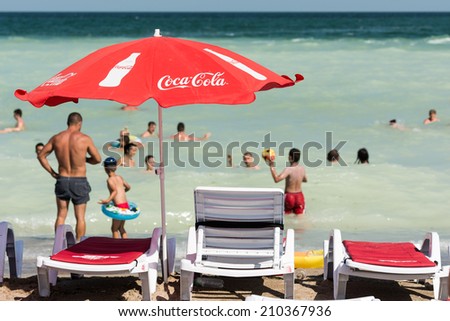MAMAIA, ROMANIA - JULY 28, 2014: People Having Fun Under Coca Cola Umbrella On The Black Sea Beach.