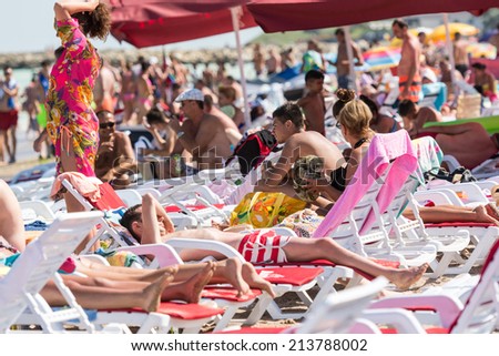 COSTINESTI, ROMANIA - JULY 31, 2014: Crowd Of Tourists Getting Sun Tanning On The Black Sea Beach In Costinesti Holiday Resort.