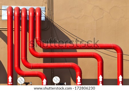 Control panel of red water pipes outside building of sprinkler fire alarm system on brown concrete wall