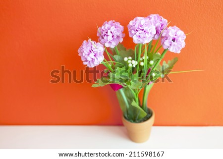 pink artificial flower made from cloth on bright orange wall, wallpaper background