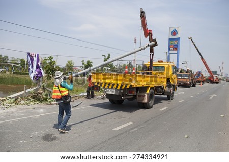 MUENG, MAHA SARAKHAM/THAILAND  MAY 2015: Officers salvage the broken pole  besides highway due to heavy rain disaster on May 1, 2015 in Maha Sarakham. Storm occurred at night of April 30, 2015.